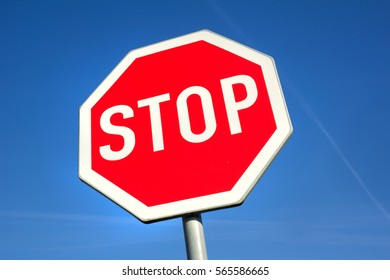 Stop traffic sign. Red octagon with white letters. Clear blue sky is behind road sign.