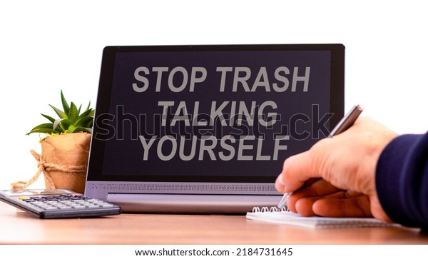 Stop trash talking yourself symbol. Concept words\
Stop trash talking yourself on the black tablet. Businessman hand\
with pen. Psychological stop trash talking yourself concept. Copy\
space.