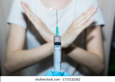 Stop vaccinations. Say no to the coronavirus vaccines. A syringe in the doctor’s hand and a refusing patient says NO. Hand stop sign. Coronavirus vaccine covid-19 2019-ncov - Shutterstock ID 1715132362