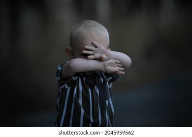Stop violence against children, stop human trafficking, domestic abuse concept, blond little boy covering his face with his hands, image blur