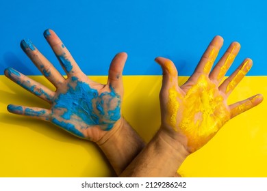 Stop war, conflict between Ukraine and Russia. Hands of a man painted with the colors of the Ukraine flag, blue and yellow background