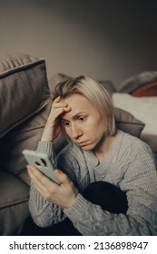 Stop The War. Pray For Ukraine. We Are Available To Ukraine. Ukrainian Frightened Woman Reads War News On Her Phone. The Woman Is Afraid Of The Sounds Of Air Raids And Explosions. The Concept Of Fear