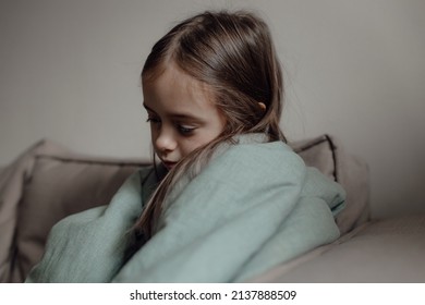 Stop war. Pray for Ukraine. we stand with Ukraine. Ukrainian frightened child under a blanket. The girl is afraid of the sounds of air raids and explosions. Poor child feeling sorrow and sadness.