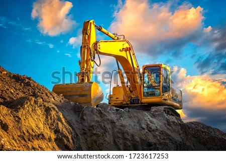 A stopping yellow excavator at an incredibly beautiful sunset