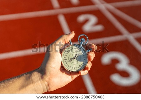 Stopwatch in hand, track numbers background, timing, sports, competition, measuring performance