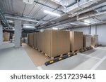 Storage area filled with neatly stacked pallets of brown boxes in a well-lit warehouse