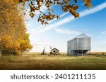 Storage bins and grain augers in a farmyard after fall harvest on the Canadian prairies in Kneehill County Alberta Canada.