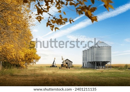 Storage bins and grain augers in a farmyard after fall harvest on the Canadian prairies in Kneehill County Alberta Canada.