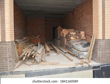 The Storage Of Building Materials Such As Bricks, Wooden Planks, Rafters, And Roof Beams Inside Of The Unfinished House Garage Under Construction.