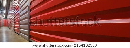 Storage corridor warehouse. Self storage facility, red metal doors with locks. Moving, organizing, storage concept. Panorama, banner. Selective focus