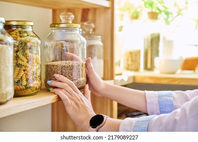 Storage of food in the kitchen in pantry, woman's hands with jar of buckwheat - Powered by Shutterstock