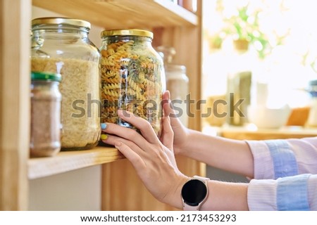 Storage of food in the kitchen in pantry, woman's hands with jar of colored paste