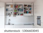Storage in the kitchen, order in the kitchen cabinets. Interior of white kitchen with red floor. Order in the house.