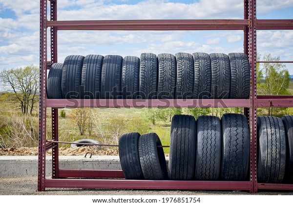 Storage and sale of old car tires. Open-air shop on\
the road.