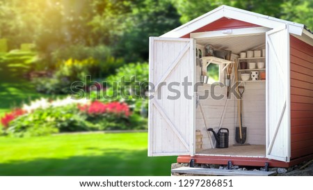 Storage shed filled with gardening tools. Beautiful green botanical garden in the background. Copy space for text and product display.