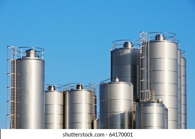 Storage Tanks Of Dairy Plant Against Blue Sky.