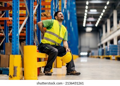A storage worker in pain having back pain and massage the painful place. - Shutterstock ID 2136431261