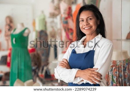 Store attendant looks at the camera and smiles in a neighborhood trade 商業照片 © 