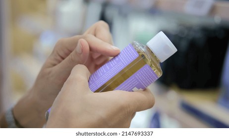 In The Store, The Buyer Reads The Information From The Manufacturer On The Goods Provided. The Goods Are Poured Into A Small Bottle Of Cosmetic. Buying Cosmetics In An Eco-shop.