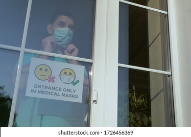 Store Employee Attaches The Sign ENTRANCE ONLY IN MEDICAL MASKS. Small Business Owner Comes Up To The Window, Glues A Warning Sign About The Obligatory Wearing Of A Face Mask Indoors, Close-up.