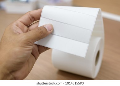 Store Man Hand Holding Sticker Paper Roll On Wooden Table Background.