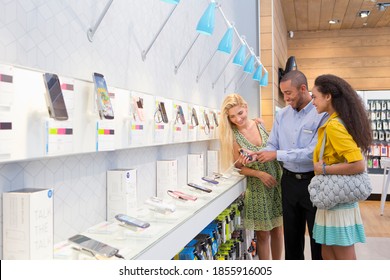 Store Manager Assisting Two Customers In A Phone Store