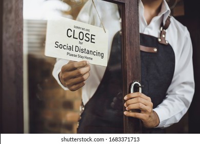 Store Owner Turning Close Sign Broad Through The Door Glass For Social Distancing Prevent Corona Virus Outbreak.