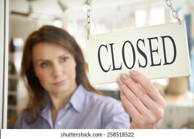 Store Owner Turning Closed Sign In Shop Doorway