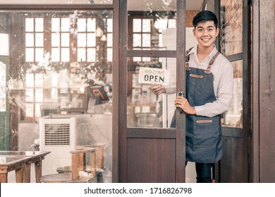 Store Owner Turning Open Sign Broad Through The Door Glass And Ready To Service.