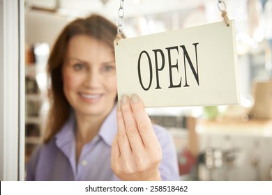 Store Owner Turning Open Sign In Shop Doorway