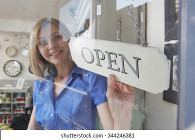 Store Owner Turning Open Sign In Shop Doorway