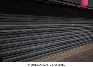 Storefront with closed metal shutter. Image of store closure or temporary closure. Metal shutter door.