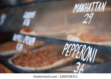 Storefront, pizza and fast food price, service and take away restaurant with closeup, shop display and window. Words, nutrition at cafe or bakery, lunch or dinner with to go meal option in New York