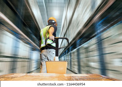 Storehouse area, Shipment. Speeding motion of warehouse worker unloading pallet goods in warehouse storage, his using with hand pallet truck.  - Shutterstock ID 1164436954