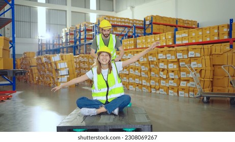 Storehouse Worker Having Fun On Job By Sitting On Pallet Jack. Happy Woman Rides Manual Pallet Jack In Storehouse. Warehouse Loader - Powered by Shutterstock