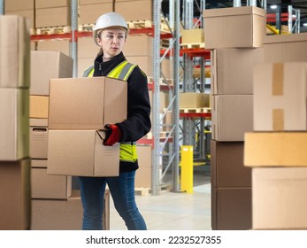 Storekeeper woman. Girl carries boxes around warehouse. Young woman with cardboard boxes. Girl storekeeper near multi-tiered warehouse racks. Storage business worker. Storekeeper in work uniform - Shutterstock ID 2232527355