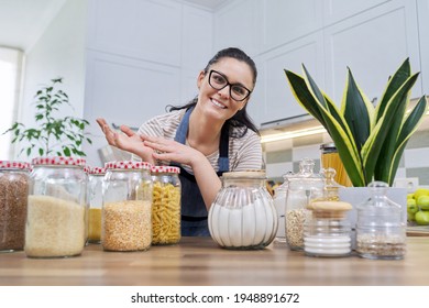 Storing food in kitchen, woman with jars and containers talking and looking at camera - Powered by Shutterstock