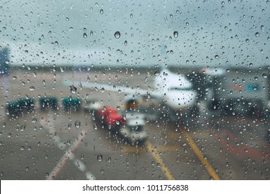 Storm At The Airport. View Of The Airplane Through Rain Drops. Themes Weather And Delay Or Canceled Flight.