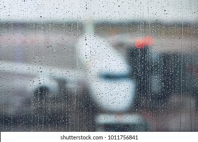 Storm At The Airport. View Of The Airplane Through Rain Drops. Themes Weather And Delay Or Canceled Flight.