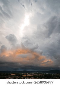 A storm is approaching, the massive clouds are lit up in a warm orange by the evening sun, and it's raining in the distance.
