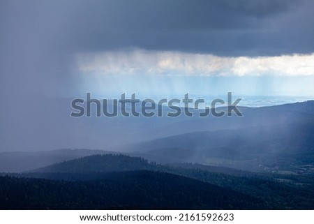 Storm cloud rain fall over mountain forest. Rainy weather cloudy sky. Fog and mist bad weather  landscape.