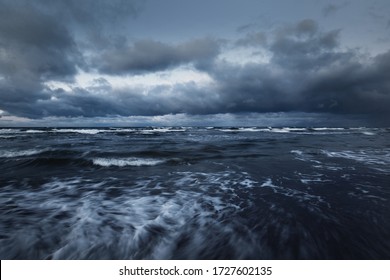 Storm Clouds Above The Baltic Sea In Winter, Long Exposure. Dramatic Sky, Waves And Water Splashes. Dark Seascape. Germany