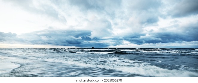 Storm clouds above the Baltic sea in winter, long exposure. Dramatic sunset sky, waves and water splashes. Dark seascape. Germany