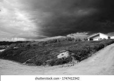 Storm The Clouds Above The Small White House On The Hill. Portugal. Europe. Black And White Photo