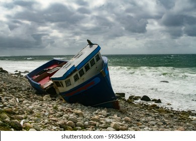 Storm Clouds Approach A Ship Wrecked Fishing Vessel Grounded On Rocky Shore Of Coastal Newfoundland, Canada