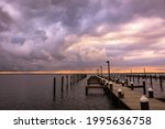 Storm clouds in the distance getting lit up with stunning sunset colors over a dock. Island Beach State Park New Jersey