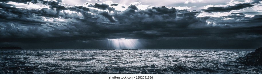 Storm Clouds Over Cold Sea Water. Stylized panoramic seascape. Dramatic sky over Lake Superior. Great Lakes view from Keweenaw County, Michigan, USA. Wide banner background with copy space.