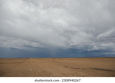 Storm clouds over a dry flat desert landscape
