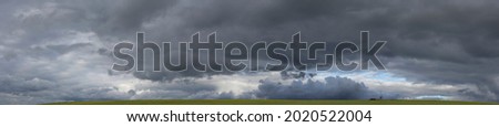 Storm clouds over the fields. Landscape at sunset. Tragic gloomy sky. Panorama. The sun is hidden.