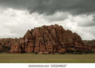 Storm Clouds Over Red Rock Formation with Green Field in Zion - Powered by Shutterstock